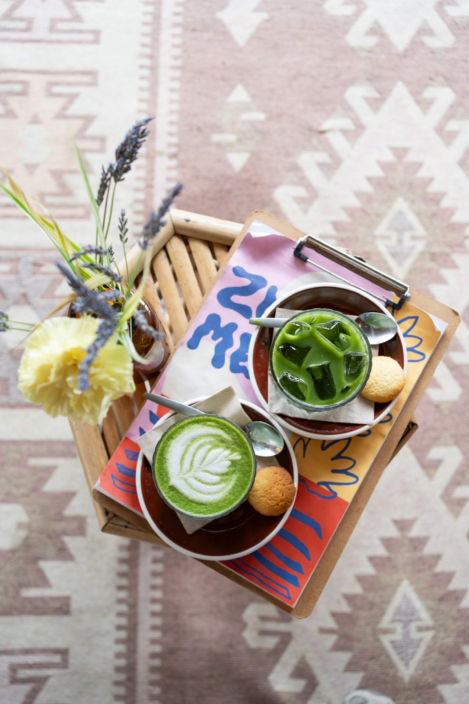 een matcha latte en een iced matcha late op een salontafel met kunstbloemen