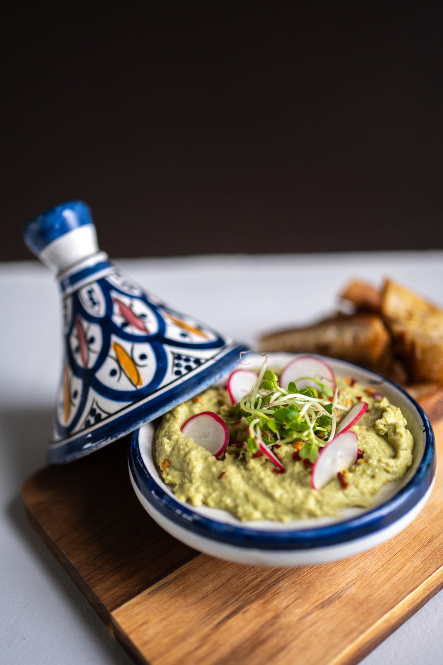 Kom groene matcha hummus met olijfolie en chilivlokken